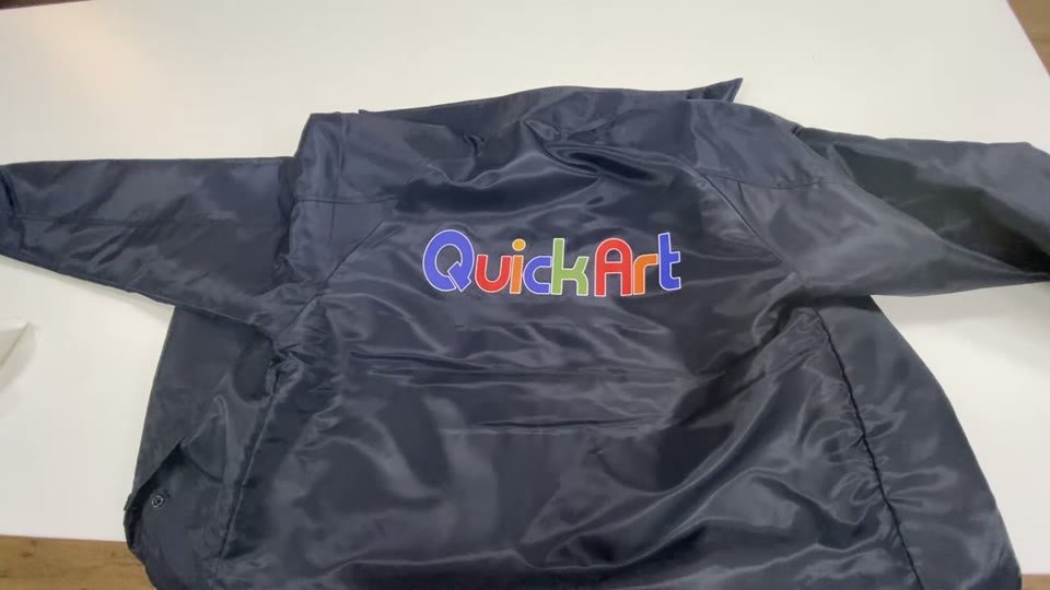紺色のポリエステルのコーチジャケットの背中に、青・赤・緑・黄色のQuickArtのロゴがプリントされた仕上がり