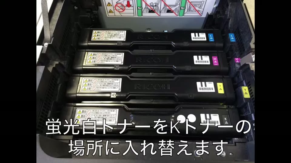 RICOHのカラーレーザープリンターのトナー4本のうち、Kトナーの場所に蛍光白トナーを入れ替えている様子