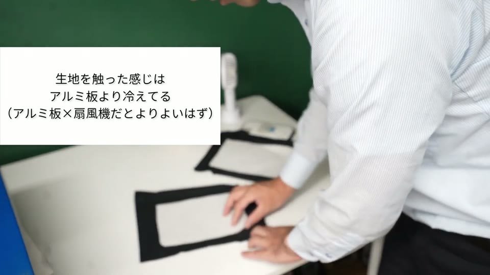 扇風機の風を当てたTシャツを手で触って確かめている。テロップに「生地を触った感じはアルミ板より冷えてる(アルミ板×扇風機だとよりよいはず)」