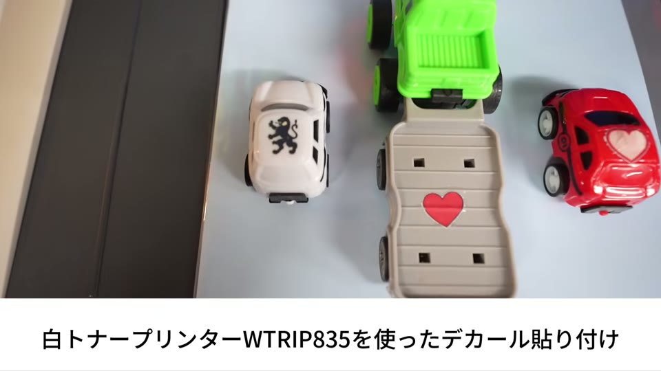 白トナープリンタWTRIP835で作ったデカールを貼ったミニカーとトラックのおもちゃ。ハートやライオンの絵柄が入っている