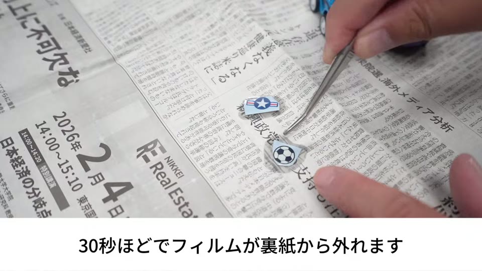 ピンセットでデカールを持ち上げ、台紙からフィルムを外している手元