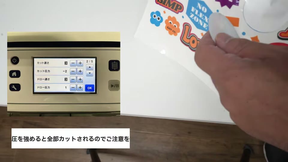 スキャンカットの設定画面(カット速さ3、カット圧力マイナス2)と、ハーフカットされたステッカーを剥がす手元。圧を強めると全部カットされるのでご注意をのテロップ