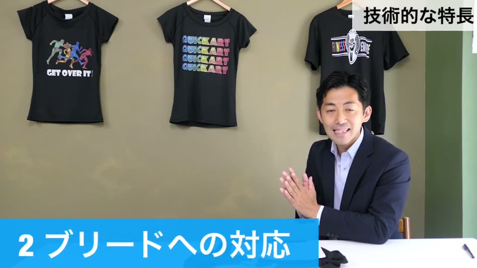 黒のTシャツが並ぶ前で、技術的な特長の2つ目としてブリードへの対応を説明する様子