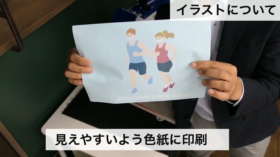 左右反転した走る男女のイラストを印刷した紙を両手で見せている様子