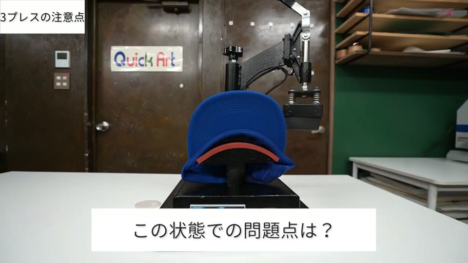 青いメッシュキャップを帽子プレス機の下ゴテにかぶせた状態。テロップはこの状態での問題点は?