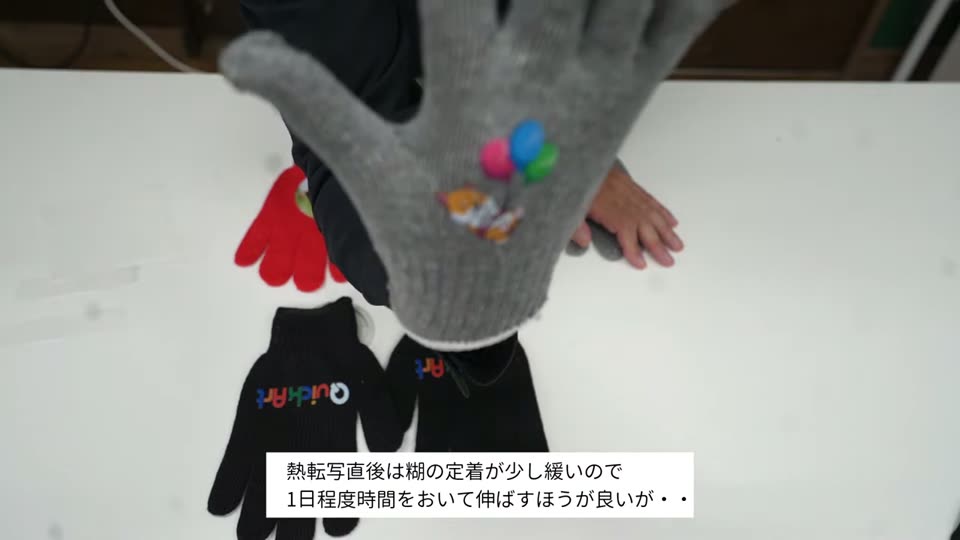 イラストをプリントしたグレーの軍手を手にはめて広げている様子。テロップは熱転写直後は糊の定着が少し緩いので1日程度時間をおいて伸ばすほうが良い