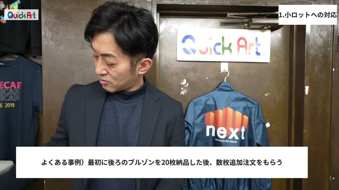 背中にnextのロゴをプリントしたブルゾンの前で説明する様子