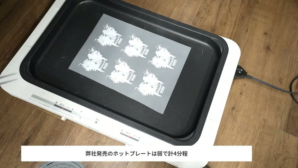 ホットプレートの上にパウダーを付けたA4のDTFフィルムを置いてベイキングしている様子