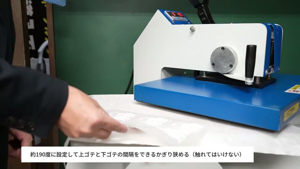 スウィング式の熱プレス機で、上ゴテと下ゴテの間を狭めてDTFフィルムをベイキングしようとしている様子