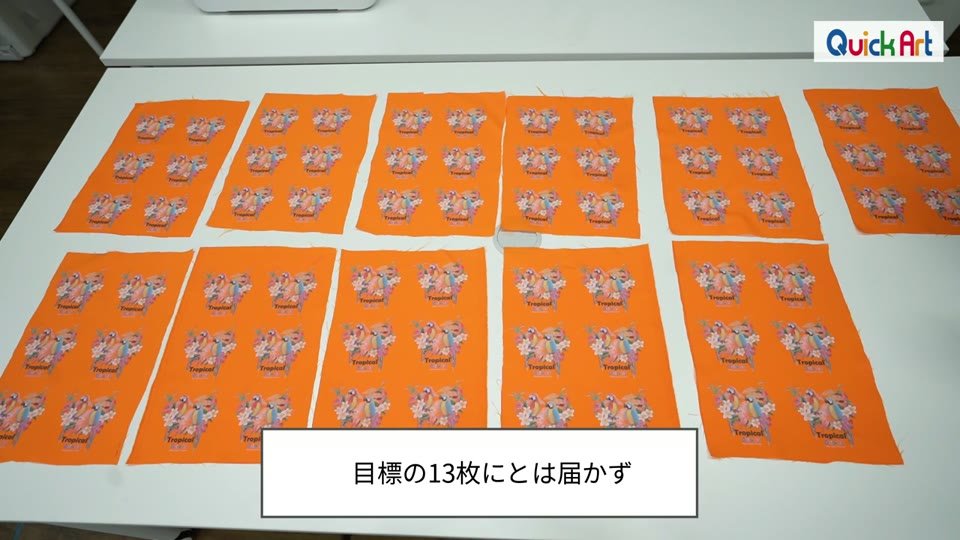 作業台いっぱいに並べた、イラストを6つずつ転写したオレンジの生地11枚。目標の13枚には届かずというテロップ
