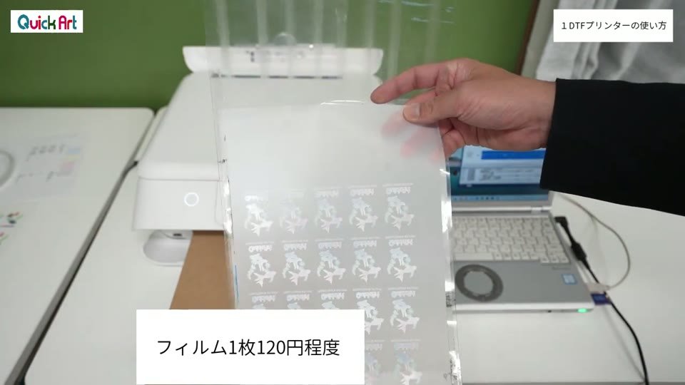 小さな金魚のイラストが並んで印刷された透明なDTFフィルムを手で持ち上げている様子