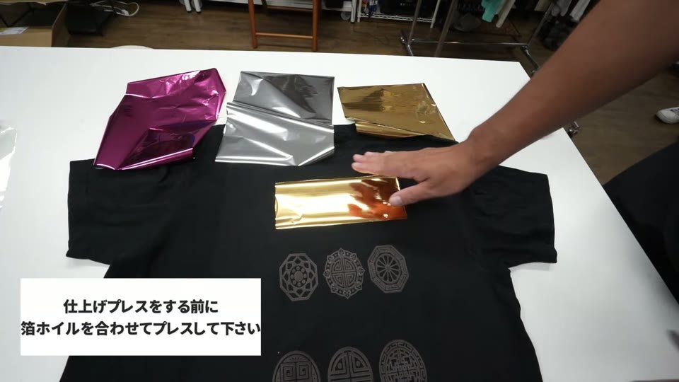 タイプWでプリントした黒いTシャツの柄の上に、ゴールドのメタリックホイルを切って置いているところ。横にピンクとシルバーのホイル