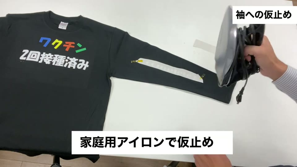 ロンTの袖に置いた転写マークに家庭用アイロンを当てている様子。家庭用アイロンで仮止めとテロップが出ている