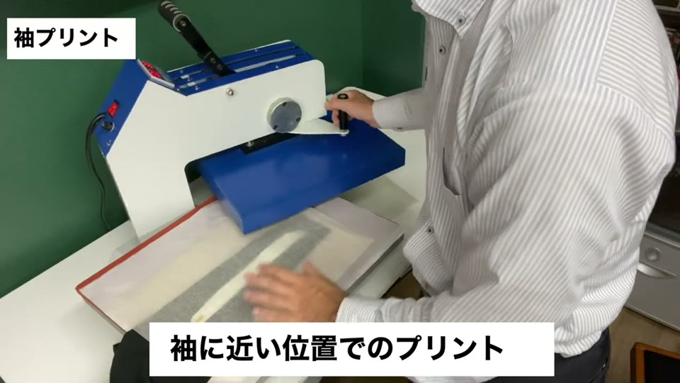 ロンTの袖をスウィング式プレス機の下ゴテに乗せてプレスする様子。袖に近い位置でのプリントとテロップが出ている