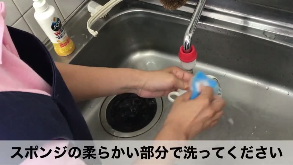 プリントしたカップを、流し台でスポンジの柔らかい部分を使って洗っているところ