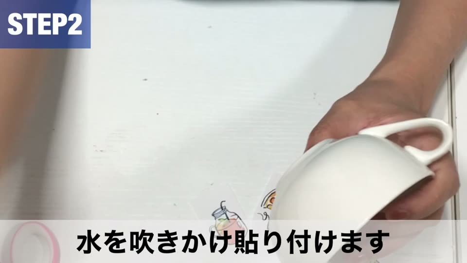 霧吹きで水をかけたカップに、オーブンプリントシートのフィルムを貼り付けているところ