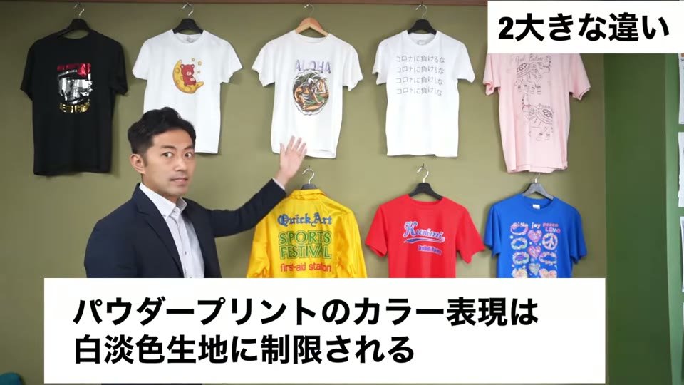 白・ピンク・黒のTシャツと、黄色・赤・青のTシャツが壁に掛けられた前で、パウダープリントのカラー表現は白淡色生地に制限されるというテロップ