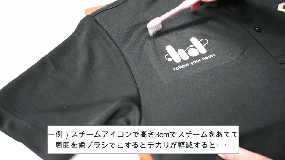 ポロシャツのプリントのまわりを歯ブラシでこすっている様子と、スチームアイロンで高さ3cmでスチームを当てて周囲を歯ブラシでこするとテカリが軽減するというネットの情報を紹介するテロップ