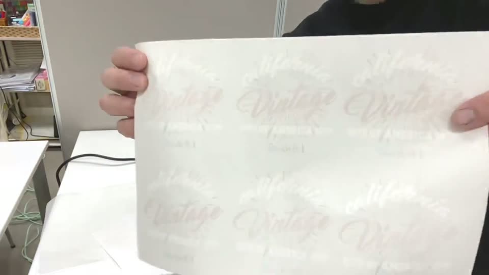 糊付けが終わったタイプWのシートを広げて見せている様子。糊が文字の部分だけに付いている
