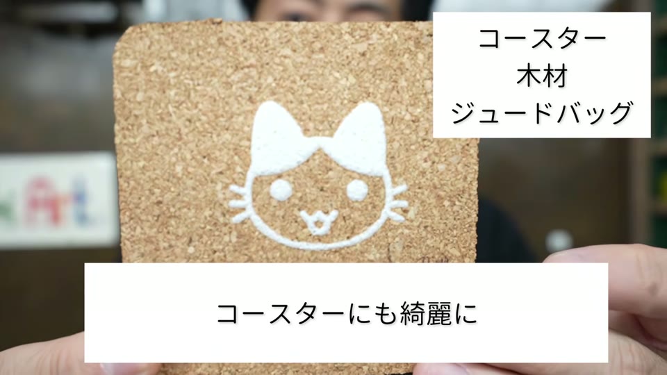 コルクのコースターに、白のぷくぷくプリントで猫の顔をプリントしたもの