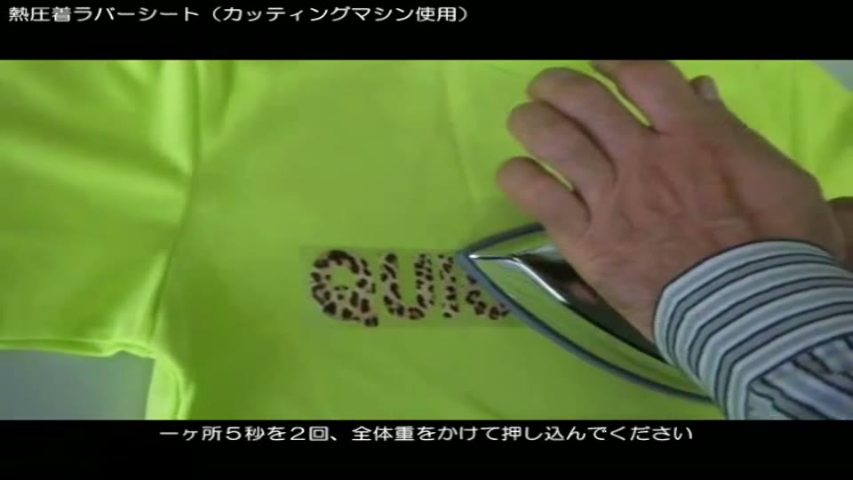 蛍光イエローのTシャツに置いた柄入りラバーシートの文字を、アイロンで体重をかけて押さえているところ