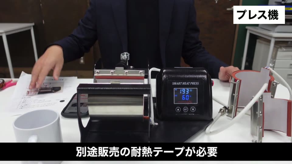 マグカッププレス機の前に置いた耐熱テープとマグカップ。別途販売の耐熱テープが必要というテロップ