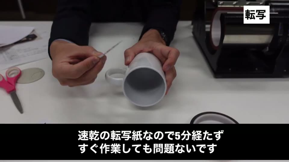 白いマグカップに転写紙を巻きつけ、耐熱テープで止めている手元