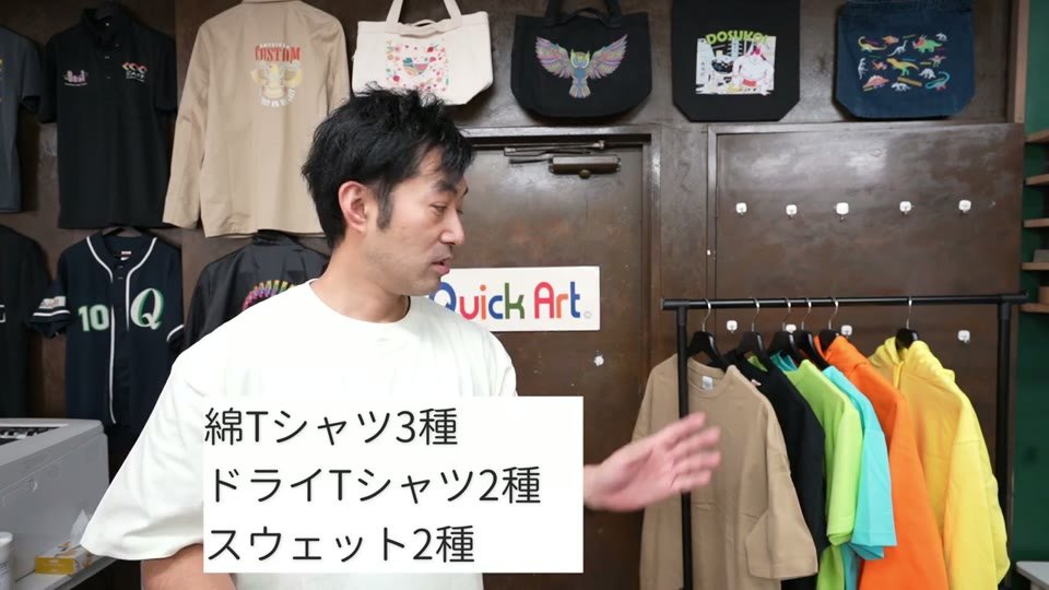 東京ショールームで、ハンガーに掛けた色とりどりのUnited AthleのTシャツとパーカーを指して紹介している様子