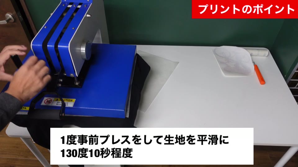 スウィング式プレス機でパーカーを事前プレスしている様子。1度事前プレスをして生地を平滑に130度10秒程度とテロップが出ている