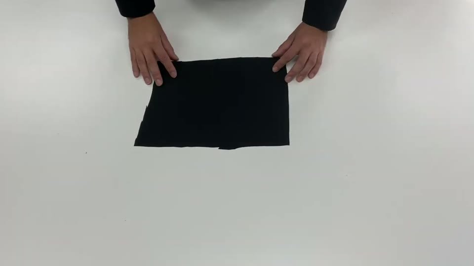 プレスした黒い生地を裏返し、転写紙の面を下にして作業台に置いている様子