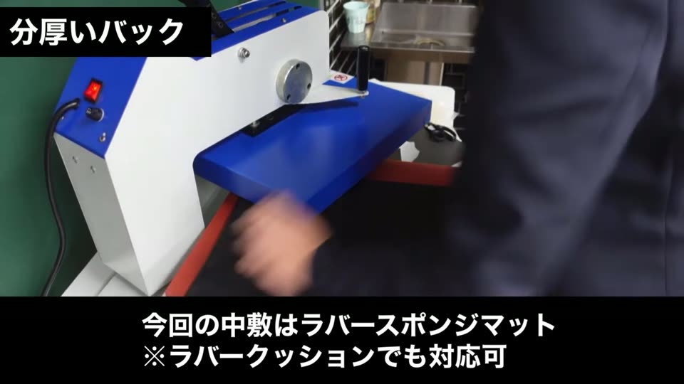 プレス機の下ゴテにかぶせた黒い分厚いバッグの中に中敷を入れている様子。テロップは今回の中敷はラバースポンジマット、ラバークッションでも対応可