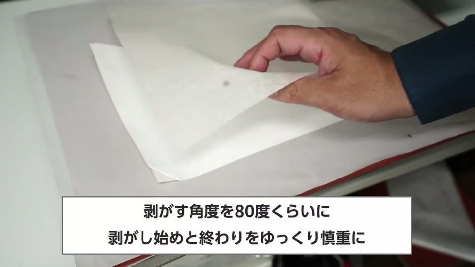 糊シートの角をつまんで剥がし始めている手元と、剥がす角度を80度くらいに、剥がし始めと終わりをゆっくり慎重にの字幕