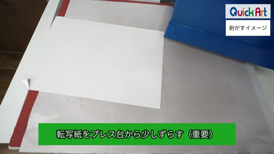 プレス台の上の転写紙を、角だけ台の端から少しずらしている手元と、転写紙をプレス台から少しずらす（重要）の字幕