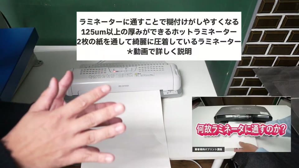印刷シートと糊シートを重ねてホットラミネーターに通している様子