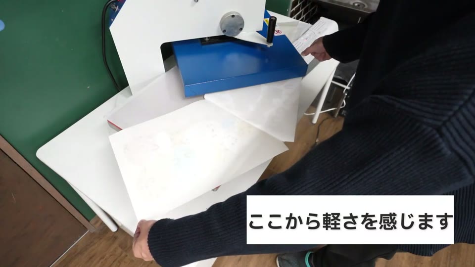 プレス機から出したA3のシートを両手で剥がしているところ