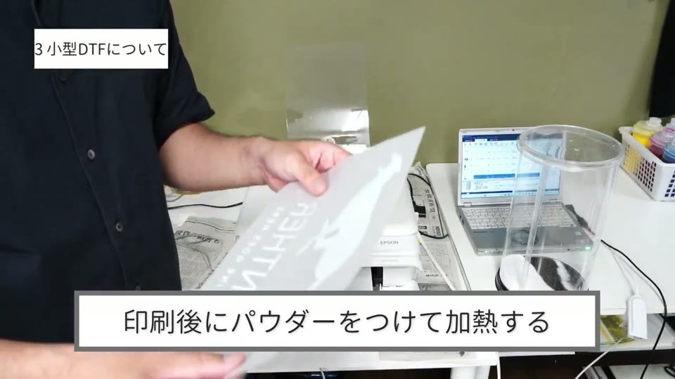 小型DTFで白いパンサーのイラストを印刷したフィルムに、パウダーをかけようとしている様子