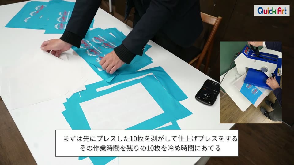 プレスを終えた生地から転写紙を剥がしている様子。まずは先にプレスした10枚を剥がして仕上げプレスをする、その作業時間を残りの10枚を冷め時間にあてるというテロップ