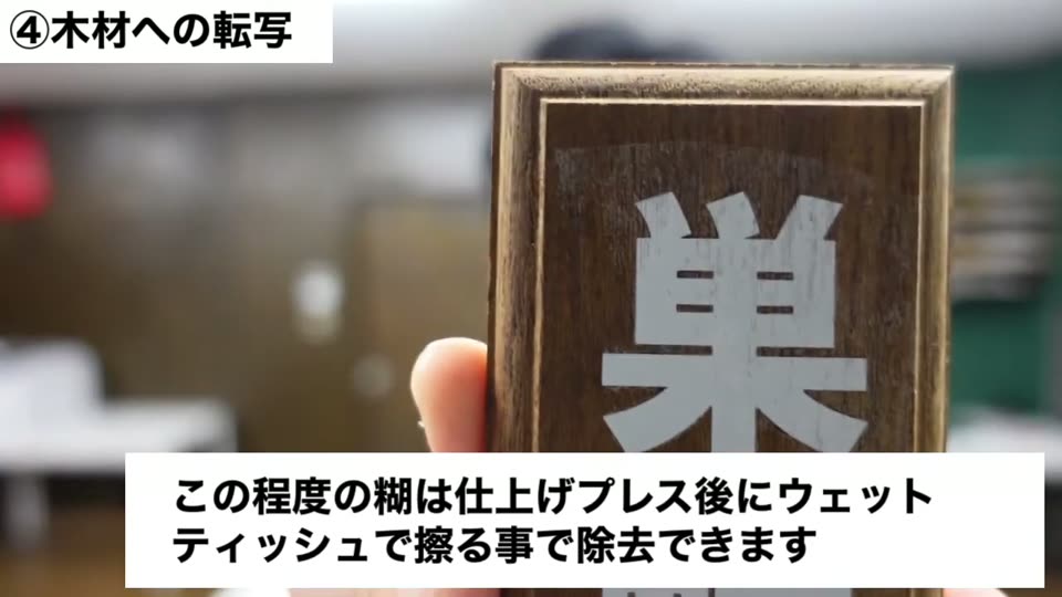 額縁付きの濃い茶色の板に「巣鴨」の白い文字を転写。糊はウェットティッシュで除去できるというテロップ